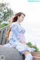 A woman in a blue dress sitting on a stone wall.