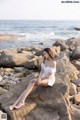 A woman sitting on a rock by the ocean.