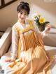 A woman in a yellow and white hanbok sitting on a bed.