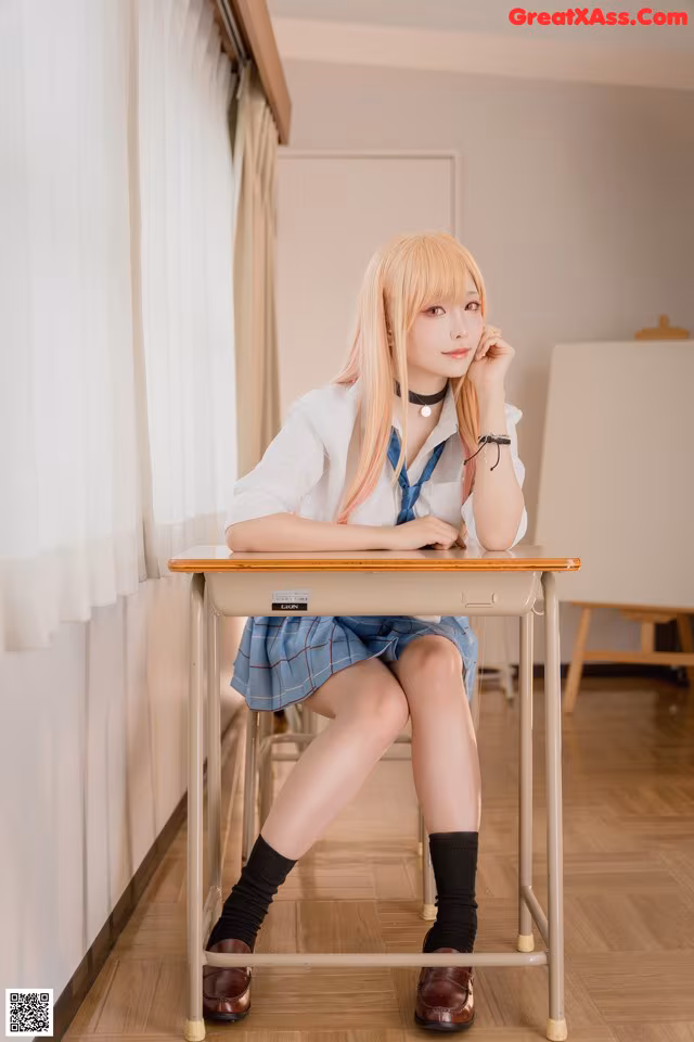 A woman sitting at a desk in a classroom.