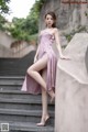 A woman in a pink dress is posing on some steps.