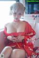 A woman in a red kimono sitting on a bathtub.