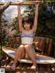 A woman in a bikini sitting on a surfboard.