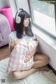 A woman sitting on a bed with a pillow and headphones on.