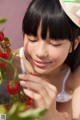 A woman in a straw hat picking tomatoes from a plant.