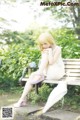 A woman sitting on a bench with an umbrella.
