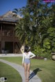 A woman in a blue and white one piece swimsuit walking down a path.