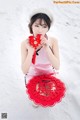 A woman in a pink dress holding a red paper fan.