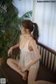 A woman in a white lingerie sitting on a bench.