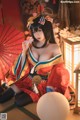 A woman in a red and blue kimono sitting on the floor.