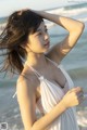 A woman in a white dress standing on the beach.