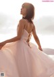 A woman in a wedding dress standing on the beach.