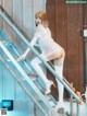 A woman in a white dress and thigh high boots on a set of stairs.