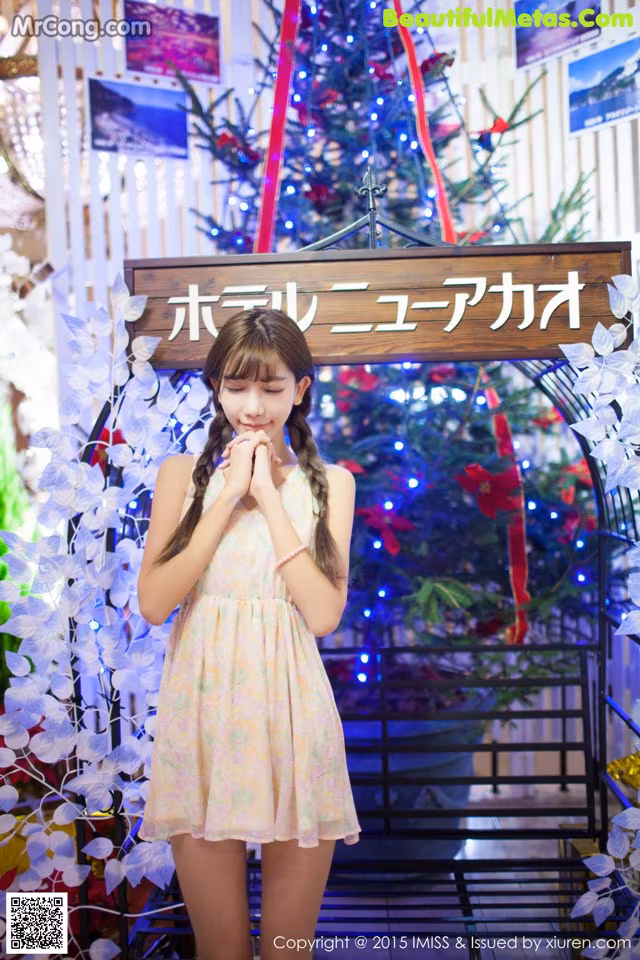 A young woman standing in front of a Christmas tree.