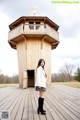 A woman standing in front of a wooden building.